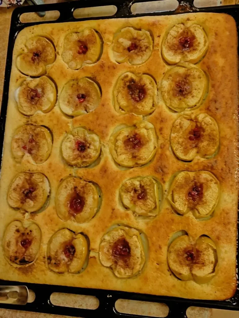 A freshly baked apple dessert with cinnamon and berries, golden and slightly crispy on top.